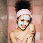 Dziewczyna z maseczką na twarzy, na ścianach różne płytki w pastelowych kolorach